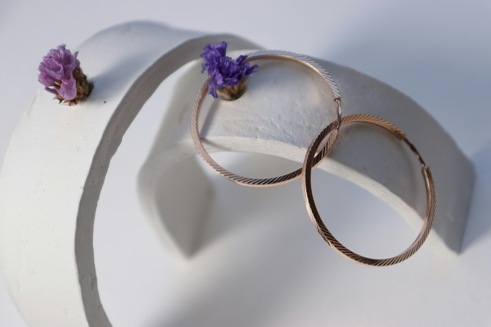 Hoop earrings and flowers on a white sculpture.