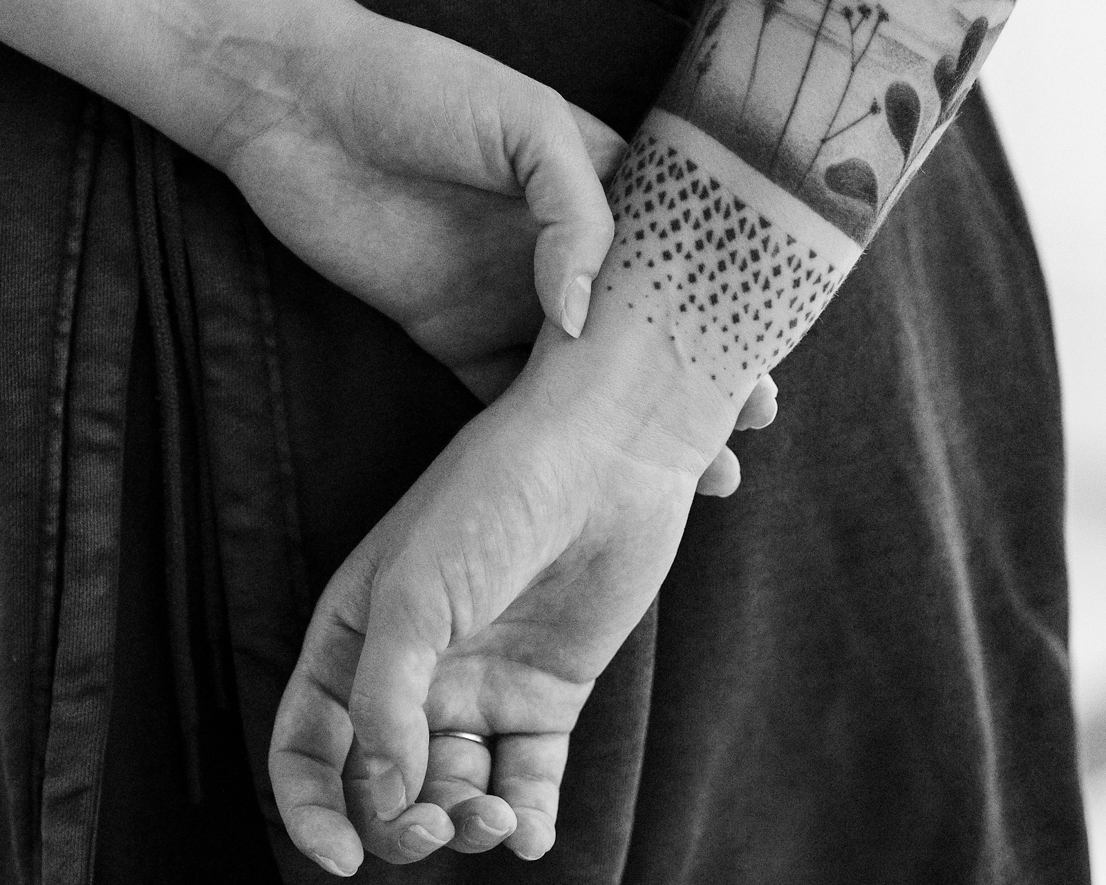 Woman's hands with tattoos behind her back