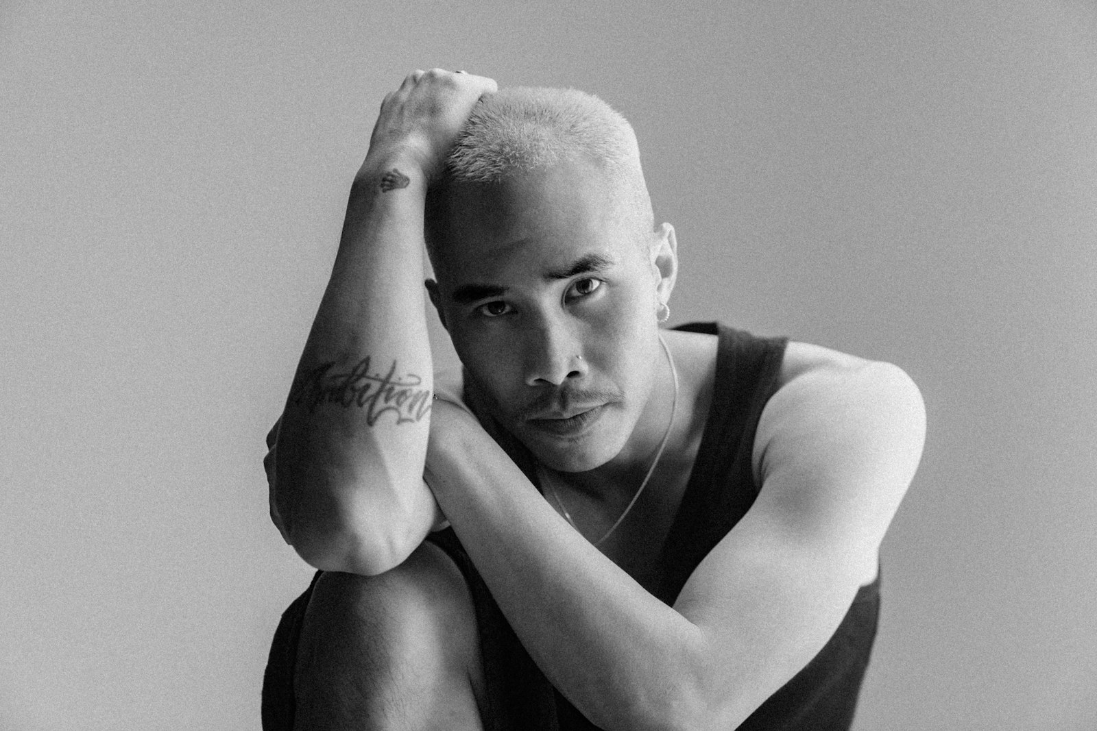 Man with blond hair and tattoos poses thoughtfully.