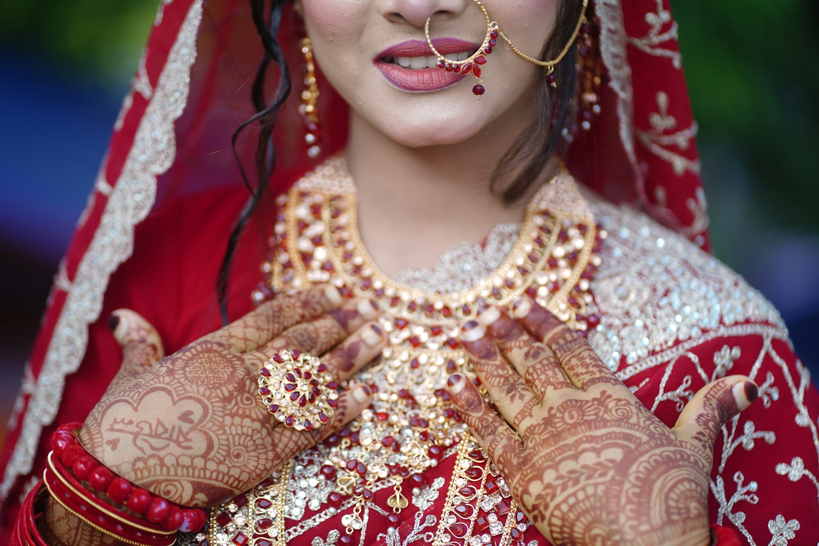 A bride adorned in traditional red attire and jewelry.