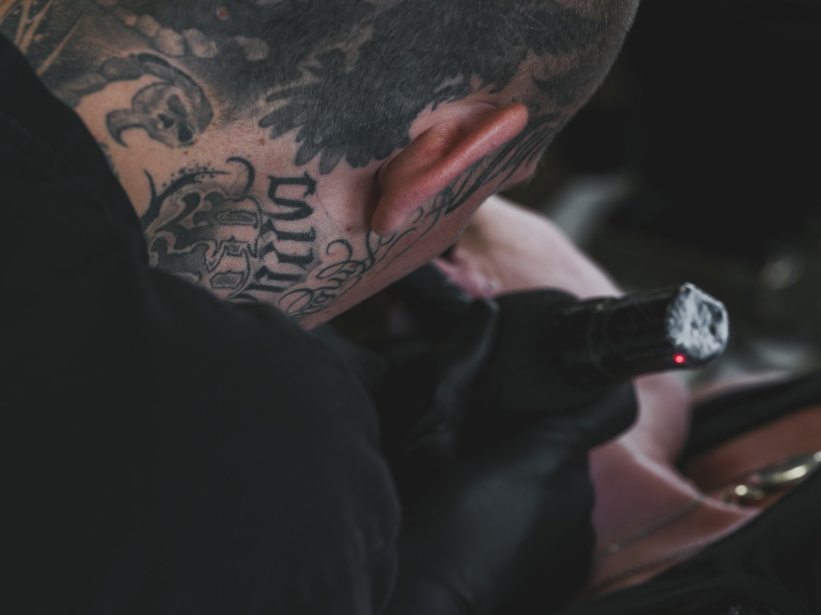 Tattoo artist working on a client's neck