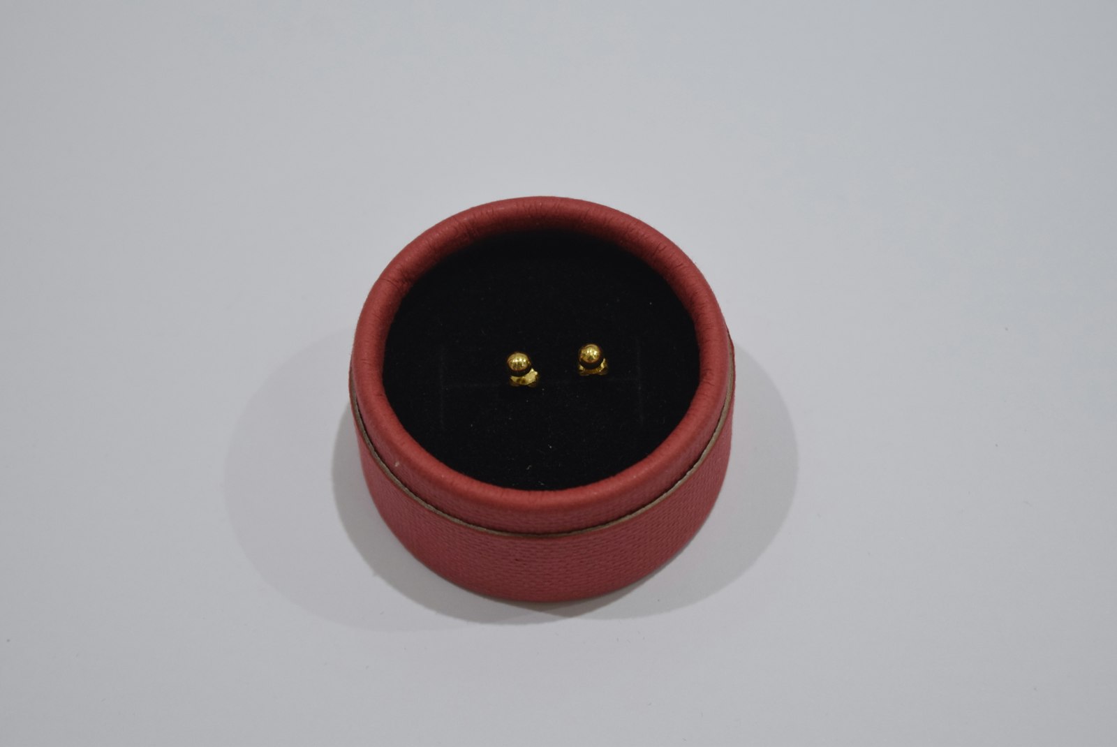 Small gold stud earrings in a red box