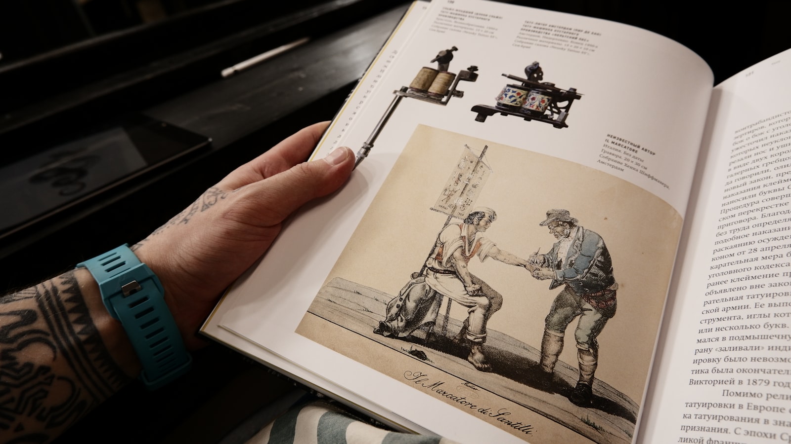 Person holding open book with tattoo machine illustrations.