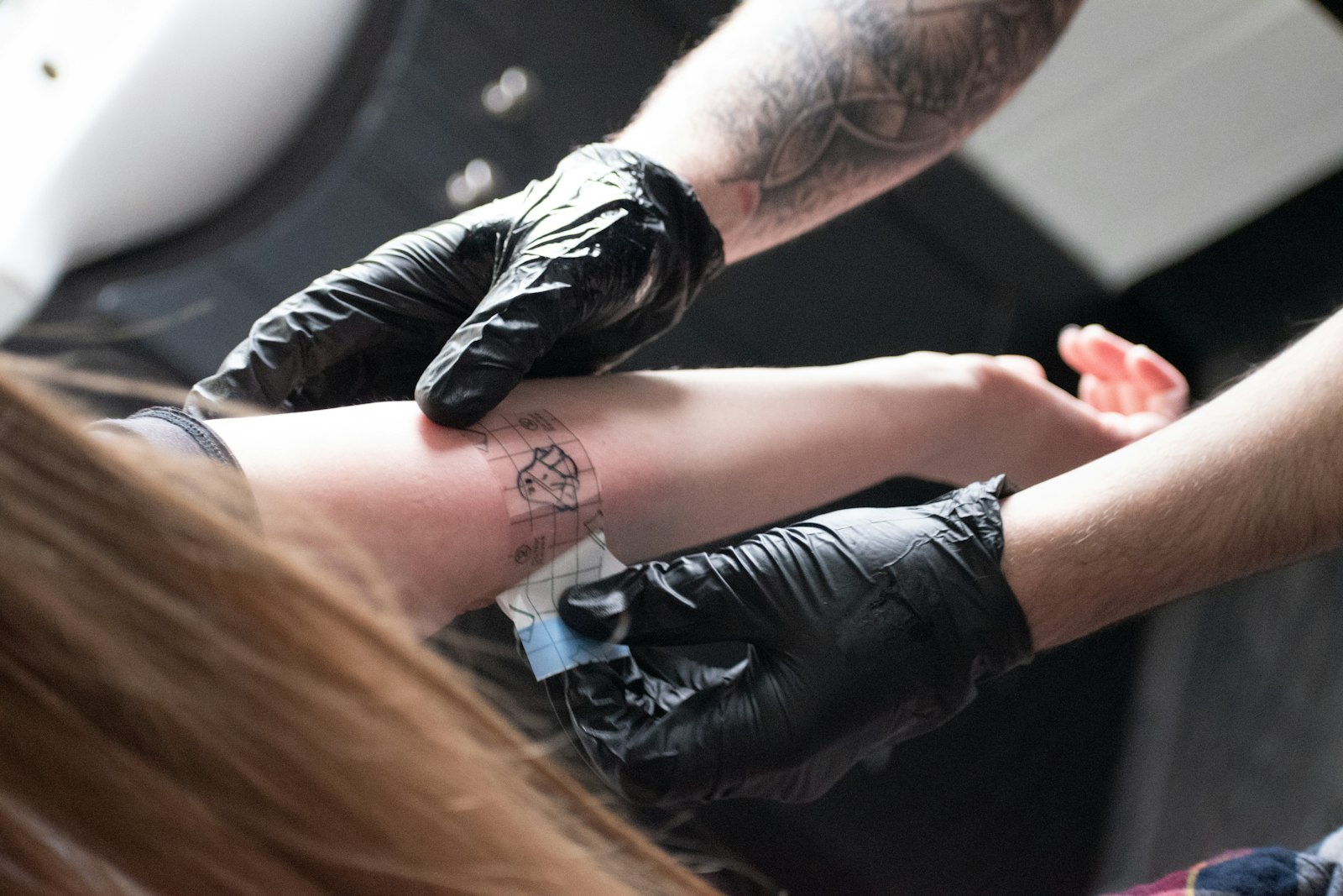 A tattoo artist is giving a tattoo.