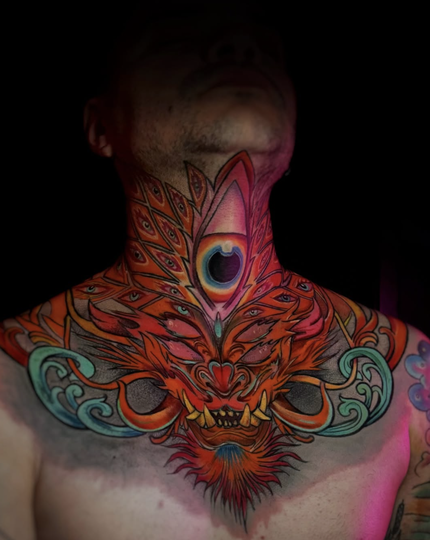 man with body tattoos raising his right arm